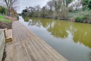 a wooden walkway next to a river at Beautiful Riverside cottage in March