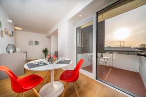 a living room with a white table and red chairs at Cozy & Bright Apartment - w/ Balcony in Udine