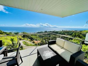 a balcony with a couch and a view of the ocean at Tahiti Moetama Cosy Lodge - VILLA ITI in Punaauia