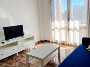 ein Wohnzimmer mit einem TV und einem Couchtisch in der Unterkunft Apartamentos El Pilar Suites 3000 in Saragossa