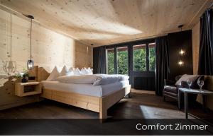 een slaapkamer met een bed, een stoel en een bank bij Hotel Arc-en-ciel Gstaad in Gstaad