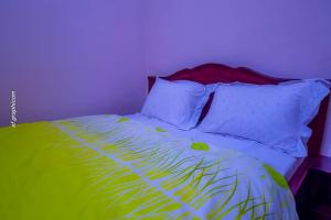 - un lit avec des draps et des oreillers verts et blancs dans l'établissement Résidence Chic & Luxueux MD & NG à Bafoussam, à Bafoussam