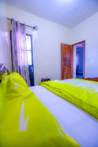 1 dormitorio con 2 camas con sábanas verdes y ventana en Résidence Chic & Luxueux MD & NG à Bafoussam, en Bafoussam