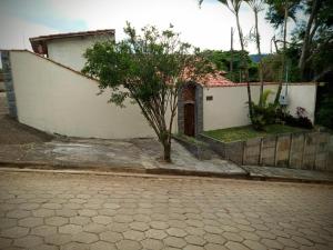 a small tree in front of a white building at Casa Colonial com lareira in São Lourenço