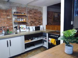 a kitchen with white cabinets and a brick wall at House of Cairo - Johannesburg in Johannesburg