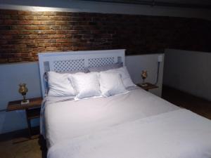 a white bed with white pillows and a brick wall at House of Cairo - Johannesburg in Johannesburg