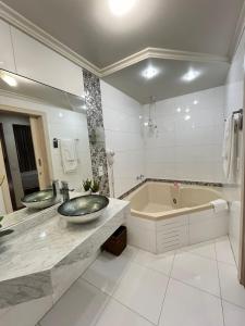 a bathroom with two sinks and a bath tub at Regente Hotel in Pato Branco