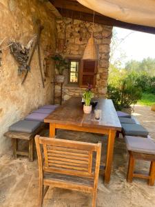 a wooden table and benches in front of a stone wall at Studio Doppelzimmer 2 Pers mit Terrasse und Pool auf Finca Mallorca in Santanyi