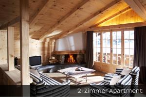 a living room with chairs and a fireplace at Hotel Arc-en-ciel Gstaad in Gstaad