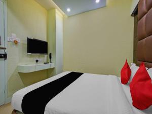 a bedroom with a bed with red pillows and a tv at Hotel Snowfox in Madhyamgram