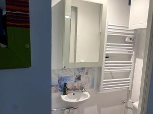 a white bathroom with a sink and a mirror at Charmante maisonnette au calme in Neuilly-en-Thelle