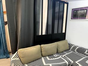 a couch sitting in a room with a window at Charmante maisonnette au calme in Neuilly-en-Thelle