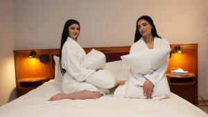 twee vrouwen op een bed met kussens bij SN Hotel and Restaurant in Langgöns