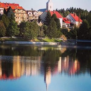 a view of a town with a reflection in a lake at Apartman Centar Fužine in Fužine