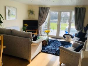ein Wohnzimmer mit 2 Sofas und einer Glasschiebetür in der Unterkunft Luxury Kingfisher Lodge, Isis Lake, within the Cotswold Waterpark in Cirencester