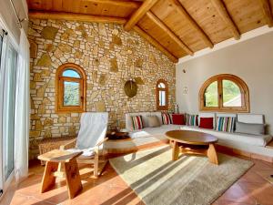 a living room with a couch and a stone wall at Villa Plaka in Afionas
