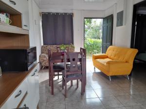 cocina con mesa, silla y sofá en La Casa de la Libélula, en Coto Brus