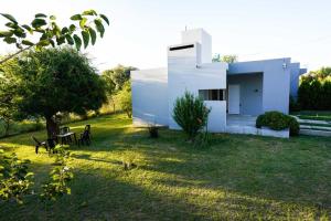 a white house in a yard with a table at Etels House - Departamentos Mina Clavero in Mina Clavero