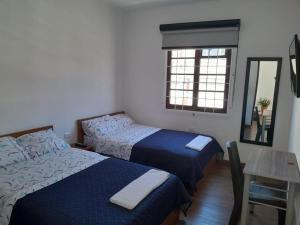 a bedroom with two beds and a table and a mirror at Casa Hotel Palermo 49 in Bogotá