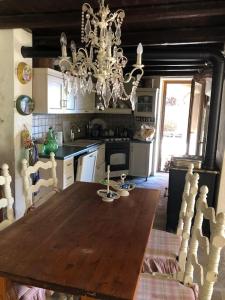 cocina con mesa de madera y lámpara de araña en Suggestivo casale in collina, en Cassano