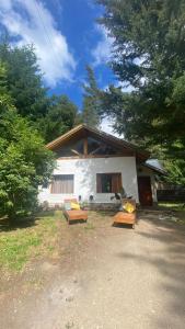 een huis met drie banken ervoor bij Cabaña Lago Nahuel Huapi - Bariloche in Bariloche