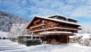 a large building covered in snow in the mountains at Hotel Arc-en-ciel Gstaad in Gstaad