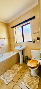 a bathroom with a toilet and a sink and a tub at A Warm 3 bed Townhouse in a secure complex in Witbank