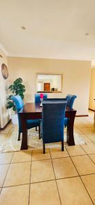 a dining room with a wooden table and blue chairs at A Warm 3 bed Townhouse in a secure complex in Witbank