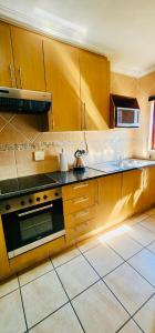 a kitchen with wooden cabinets and a stove top oven at A Warm 3 bed Townhouse in a secure complex in Witbank