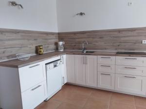 cocina con armarios blancos y pared de madera en Gîte Les Songes, en Canet