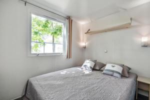 a bedroom with a bed and a window at Camping Capfun La Bretèche in Les Épesses