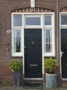 a black door on a brick house with two potted plants at Cessinas in Groningen +11 photos