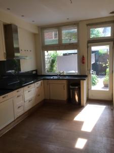 a kitchen with white cabinets and a sink and a window at Cessinas in Groningen