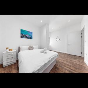 a white bedroom with a large bed and a dresser at Delta 1 Br Apartment in London DP328 in Croydon