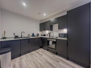 a large kitchen with black cabinets and appliances at Orange Rentals-City Centre - High Spec - The Aqua Suite, Sleeps 4 in Liverpool