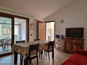 une salle à manger avec une table, des chaises et une télévision dans l'établissement Residenze S'ABBAIDA, à Tanaunella