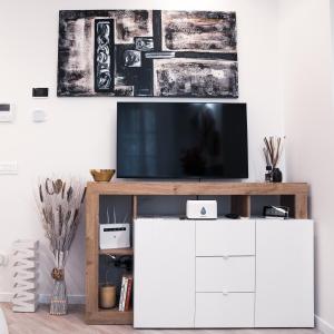 a living room with a tv on top of a white cabinet at Dimora Palazzo delle Gabette - Centro Storico in Pavia