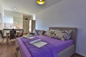 a bedroom with a purple bed and a kitchen at Buskovic Bella Vista in Dobra Voda