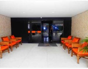 um átrio vazio com cadeiras laranja e um elevador em Ap em Maceió todo equipado á 150m da praia de Ponta Verde em Maceió