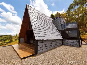 a small house with a pitched roof and a window at Cabana com hidro e natureza! in Estefânia