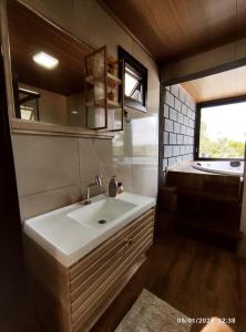a bathroom with a white sink and a window at Cabana com hidro e natureza! in Estefânia +21 photos