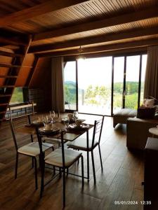 a dining room with a table and chairs and a large window at Cabana com hidro e natureza! in Estefânia
