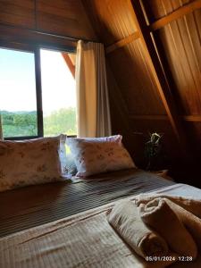 Cama en habitación con ventana grande en Cabana com hidro e natureza!, en Estefânia
