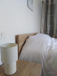 uma lâmpada branca numa mesa ao lado de uma cama em Gîte Les Songes em Canet