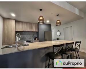 a kitchen with a sink and a counter with chairs at Nouveau Condo Québec in Quebec City