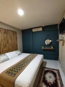 1 dormitorio con 1 cama grande y pared azul en TC Maya Abaya Hotel, en Kuantan