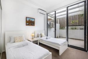 Habitación blanca con 2 camas y ventana en Central of Toowong Neat Apt Near Station en Brisbane