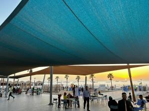 Un groupe de personnes assises à des tables sous un parapluie bleu dans l'établissement Complexe Hôtelier Sabah, à Nouakchott