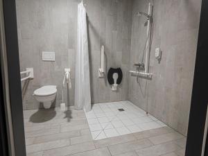 uma casa de banho com um chuveiro e um WC. em B&B HOTEL Wiener Neudorf em Wiener Neudorf