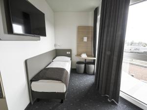 Schlafzimmer mit einem Bett, einem TV und einem Fenster in der Unterkunft B&B HOTEL Wiener Neudorf in Wiener Neudorf